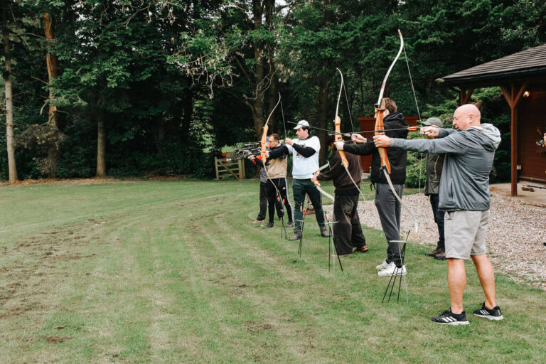 Group taking part in an archery activity at a country estate during a Peak District team building event.