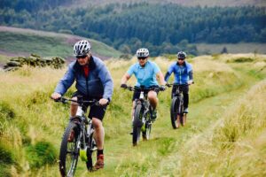 Three men cycling through the Peak District during an outdoor team experience.