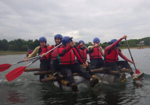 Group paddling a raft they built during an outdoor team building activity in the Peak District