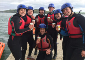 Team in wetsuits celebrating after launching their raft during a Peak District raft building challenge.