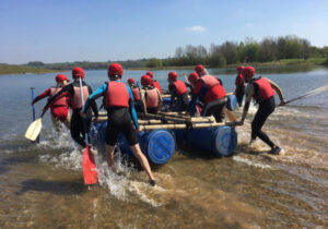 Team launching a raft they built during a Peak District raft building team challenge.