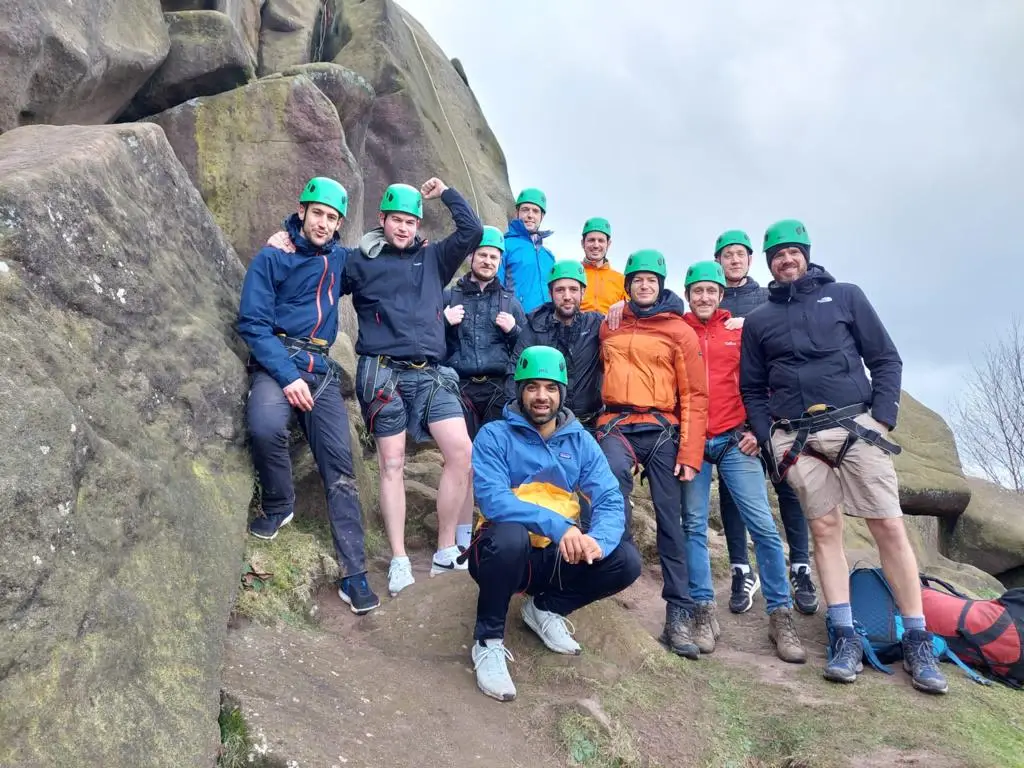 Group wearing safety gear during an abseiling team building activity in the Peak District